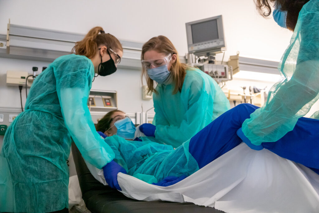 Students learning how to lift patients safely during a physician assistant program skills lab at Northeastern University
