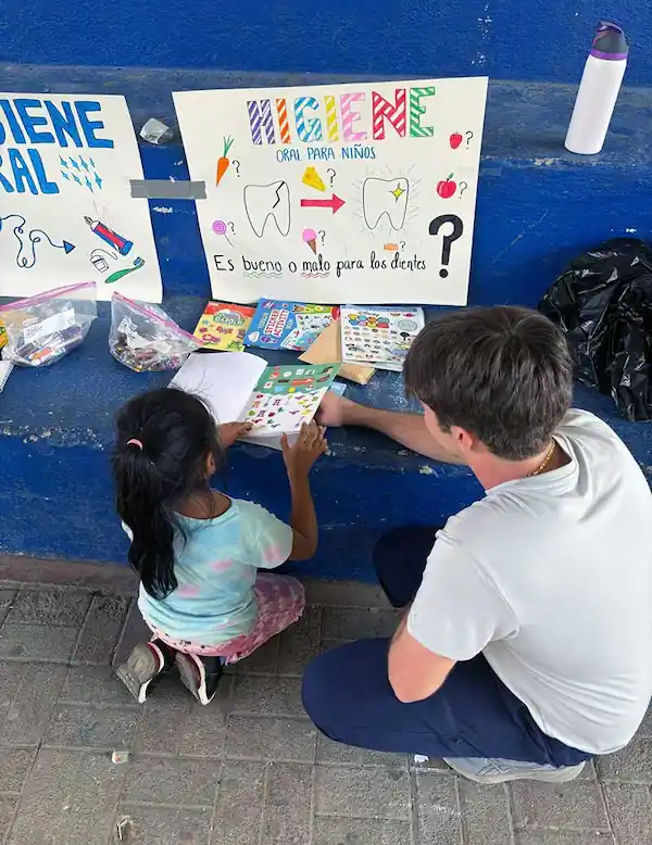 A Northeastern student helping a little girl to read a book on the street
