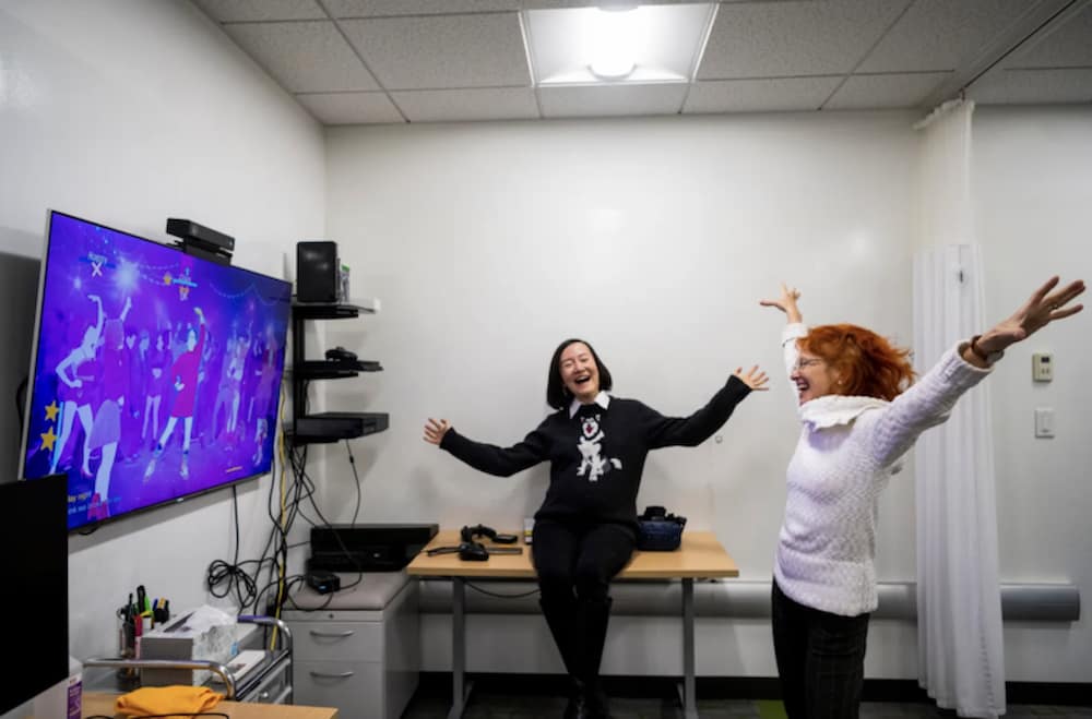 Northeastern associate professor of communication studies and health sciences Amy S. Lu and director of the Health Technology Lab Dagmar Sternad play an interactive video game