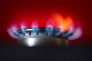 Close up photo of gas stove with blue flames and red background