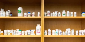 Pill bottles are shown head-on in a wooden cabinet.