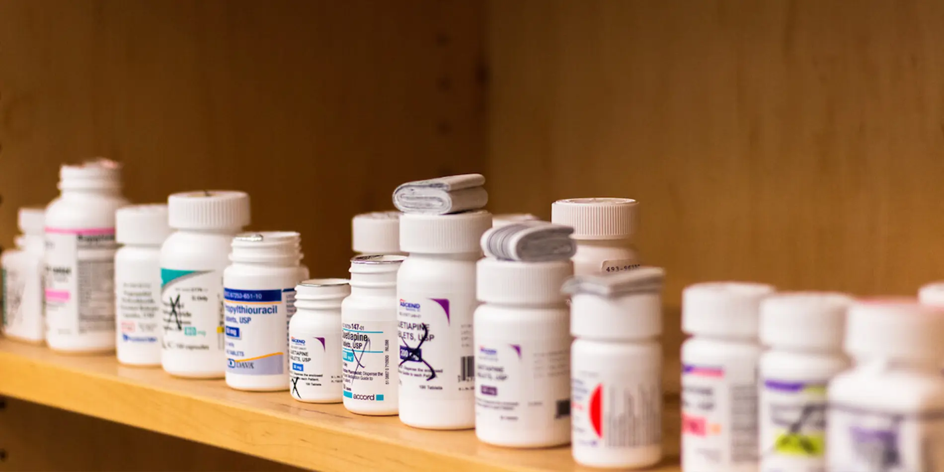 Close up of pill bottles on a wooden shelf.
