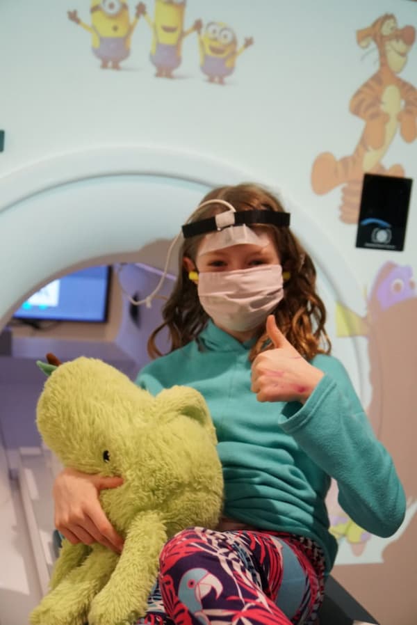 A child giving a thumbs up after in Northeastern University Biomedical Imaging Center