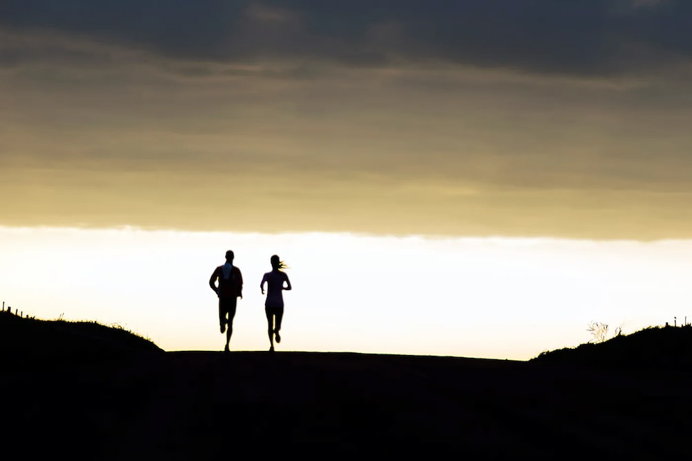 Silhouettes of two people running in the distance