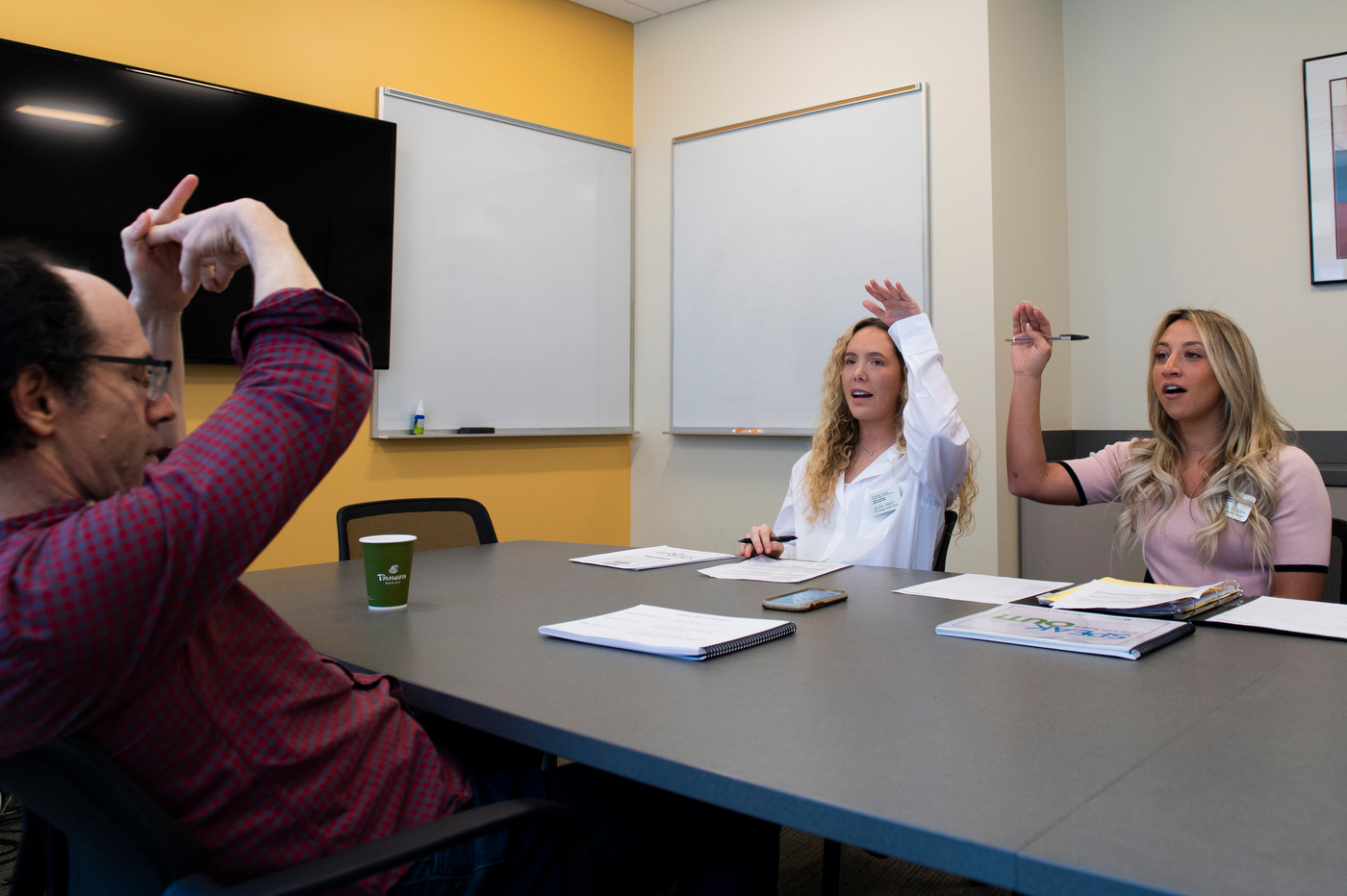 Northeastern speech language pathology graduate students Olivia Fahey and Sabrina Bender go through speech exercises with their patient Rob Jacobson