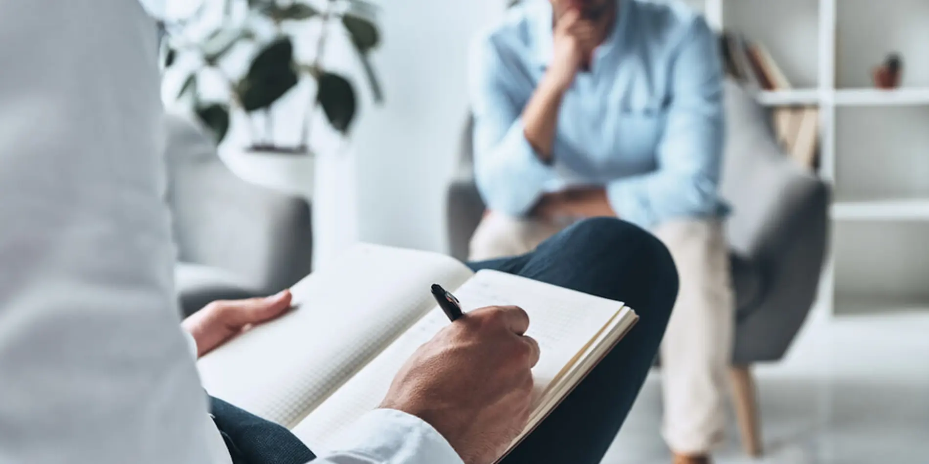 Therapist writing in notebook while listening to male patient