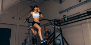 A woman is running inside with optical motion tracking markers covering her body.