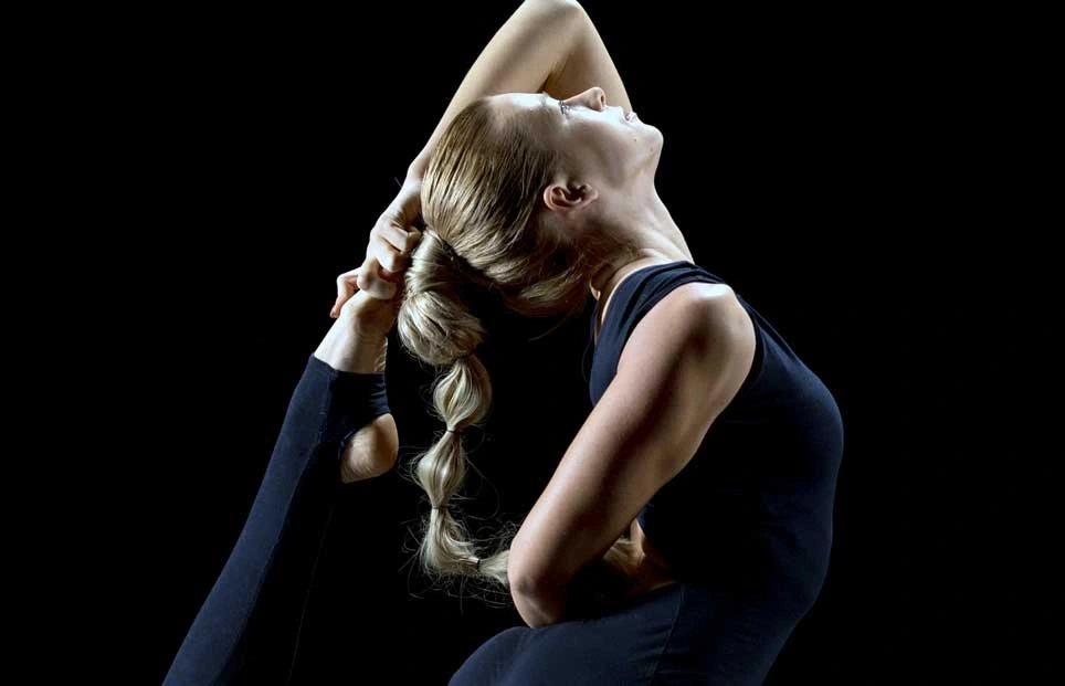 Woman stretching with her arm holding her leg behind her head.