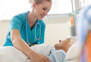 Acute gerontology nurse practitioner comforts a senior patient in her hospital bed