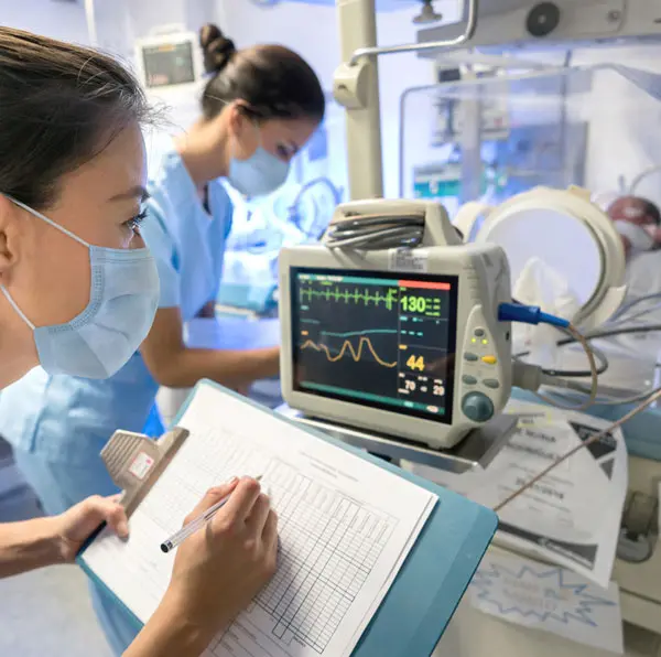 Two neonatal nurses working in an ICU