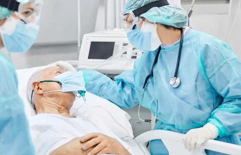 Two nurses speaking with elderly man prior to a proceedure