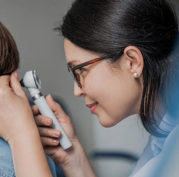 Audiologist looking in young boy's ear