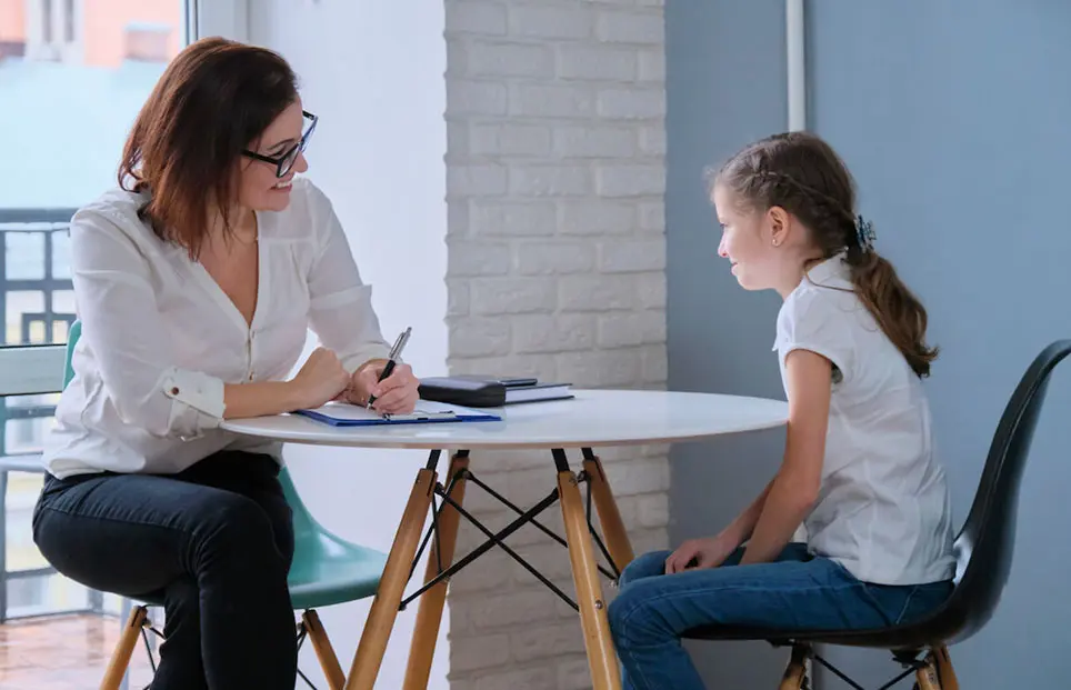 A counselor sitting at a table with a child client