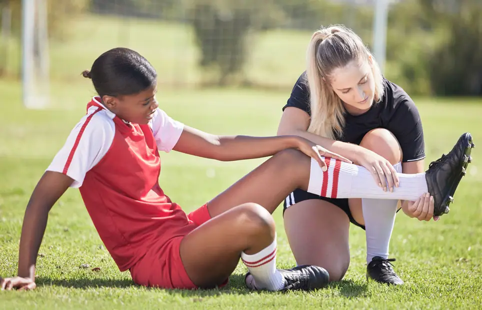 Physical therapist looking at injured athlete's leg mid soccer game