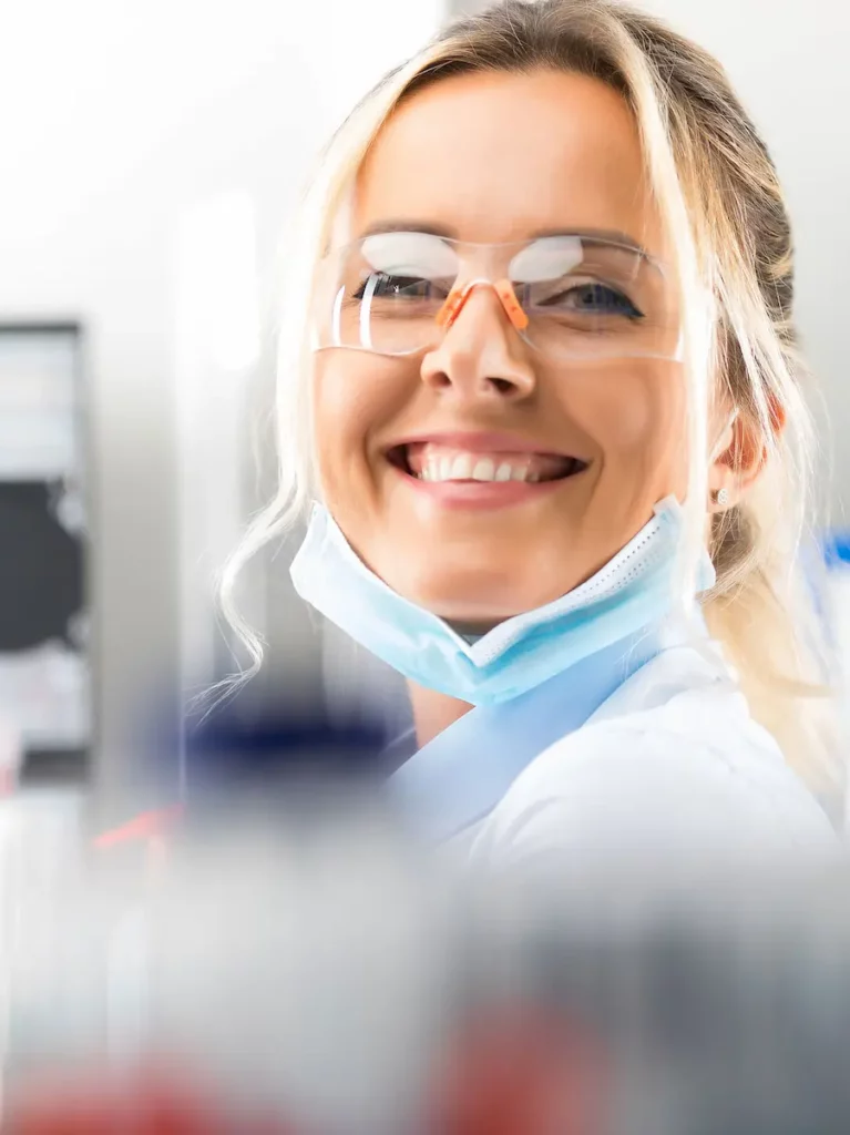 Woman in lab gear smiling at the camera warmly