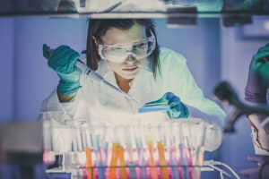 Woman doing research under a hood with test tubes