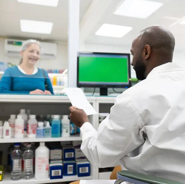 Pharmacist of color behind the counter looking at screen
