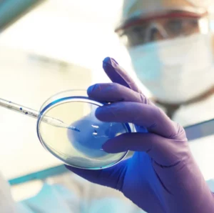 Researcher in bio-hazard gear swabbing a culture into a dish