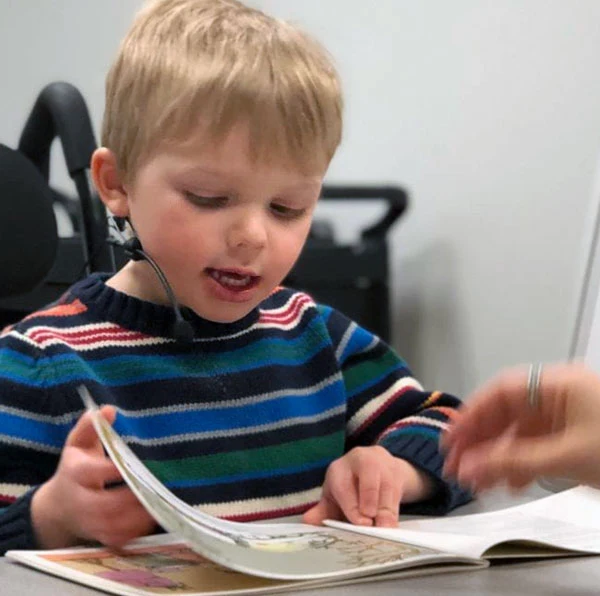 Little blonde boy reading at the SMILE Lab at Northeastern University