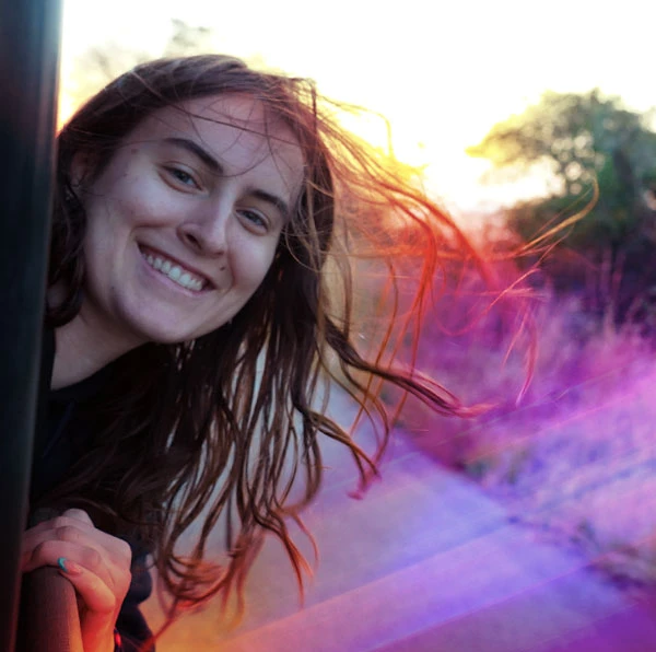 Northeastern student in South Africa leaning out safari window with her hair blowing in the wind
