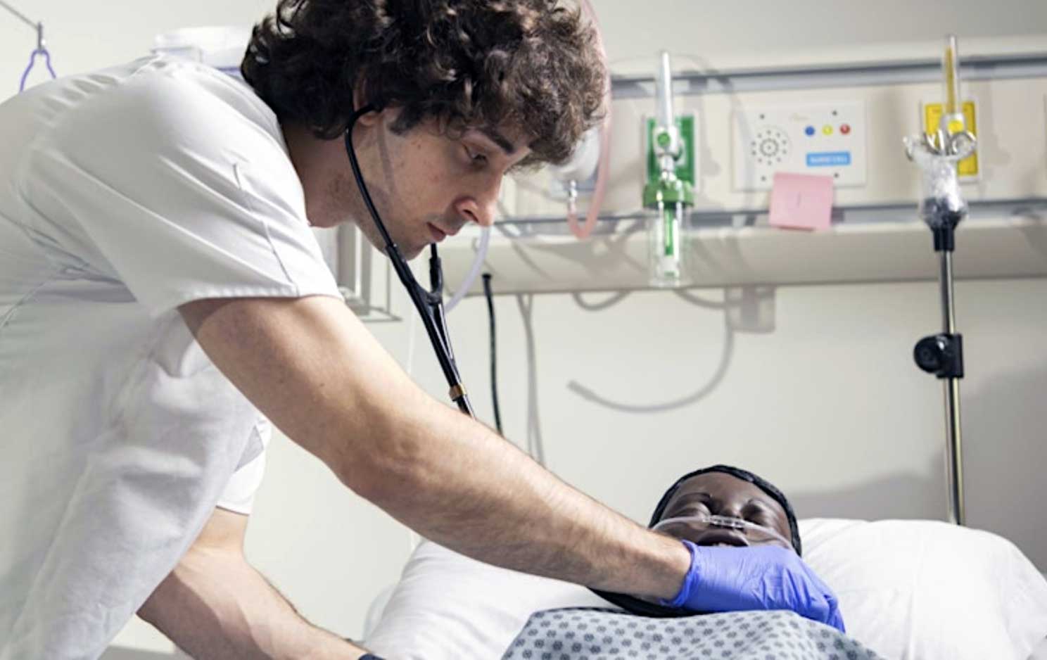 Male nursing student taking heart beat of a SIM robot