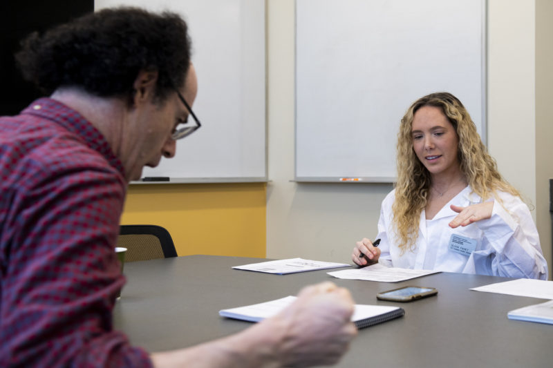 Northeastern speech-language pathology graduate student Olivia Fahey demonstrates a steady tone before a voice scale exercise with patient Rob Jacobson, who has Parkinson’s Disease. Photo by Alyssa Stone/Northeastern University