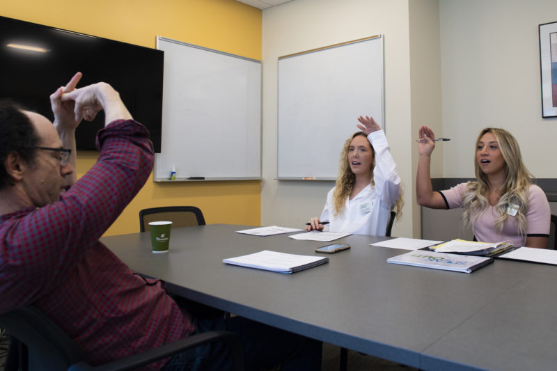 Northeastern speech-language pathology graduate students Olivia Fahey and Sabrina Bender go through speech exercises with their patient Rob Jacobson, who has Parkinson’s Disease, in the Forsyth Building on Friday, April 29, 2022. Photo by Alyssa Stone/Northeastern University