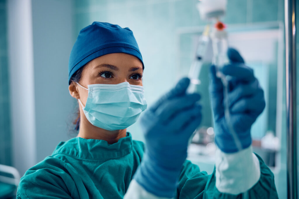 Female anesthesiologist injecting drugs through IV drip before surgical procedure in the hospital.