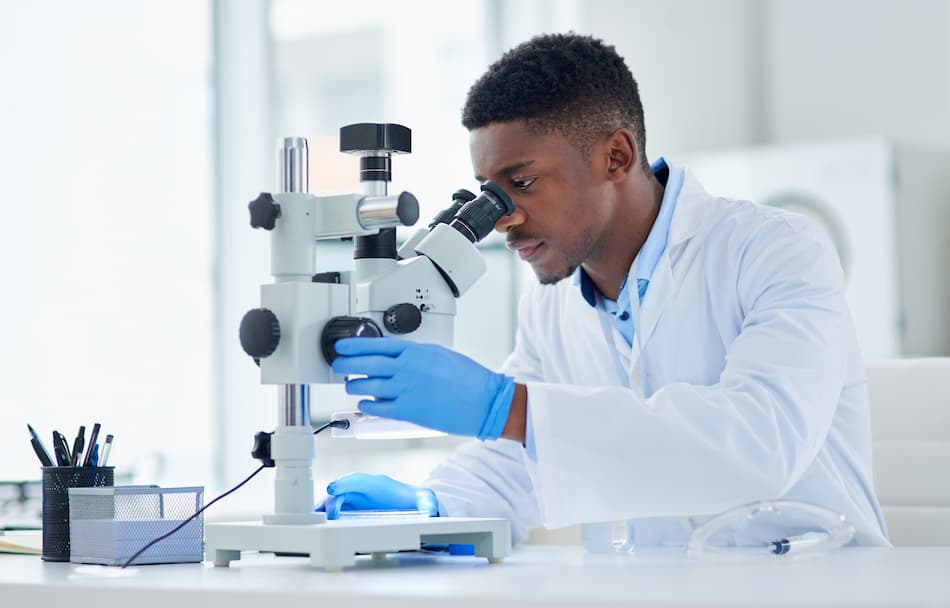 Man looking into a microscope as he works as a pharmaceutical scientist