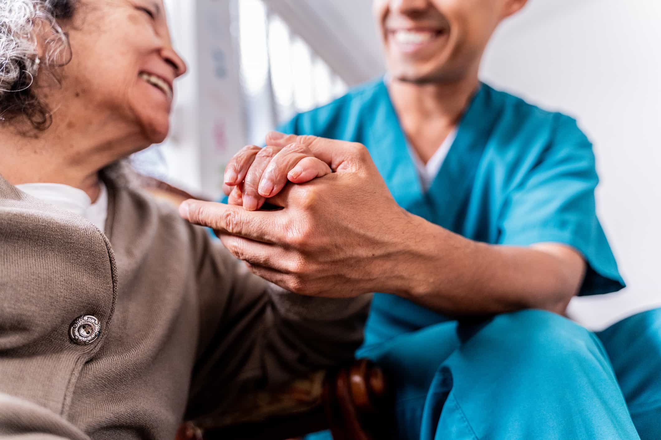 A healthcare professional holding hands with a patient.