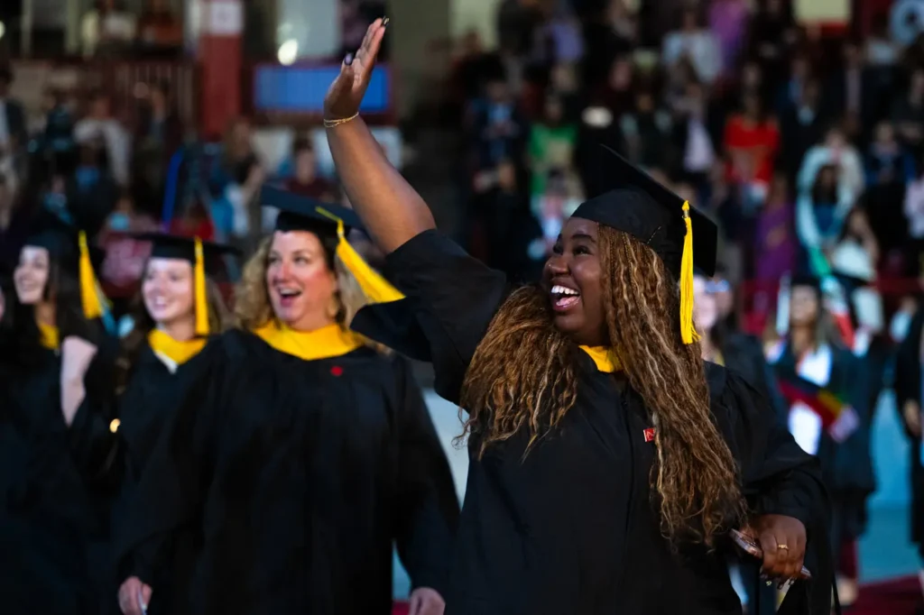 Graduates waving to families in the crowd at the Bouvé College Celebration