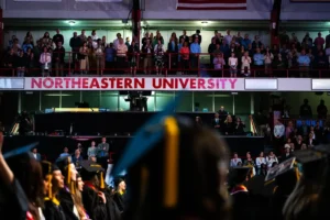 Scene from the Bouvé College Celebration featuring Northeastern University sign and families seen standing in the bleachers