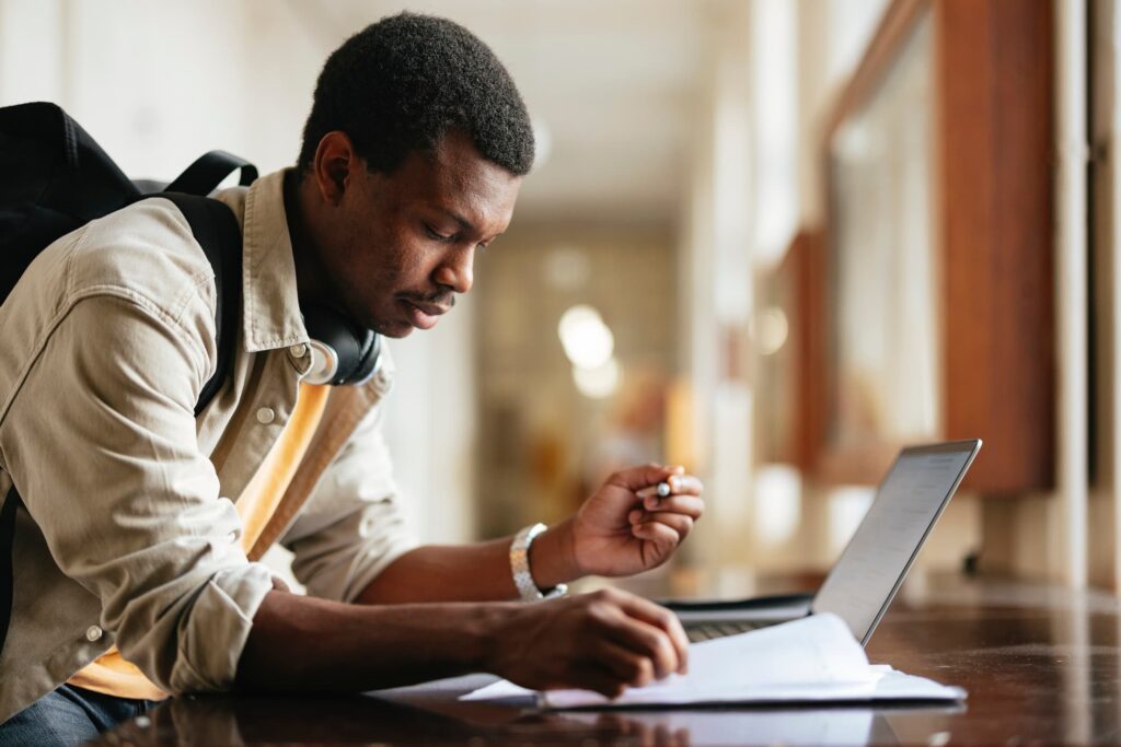 A person sitting in front of a laptop and a piece of paper.