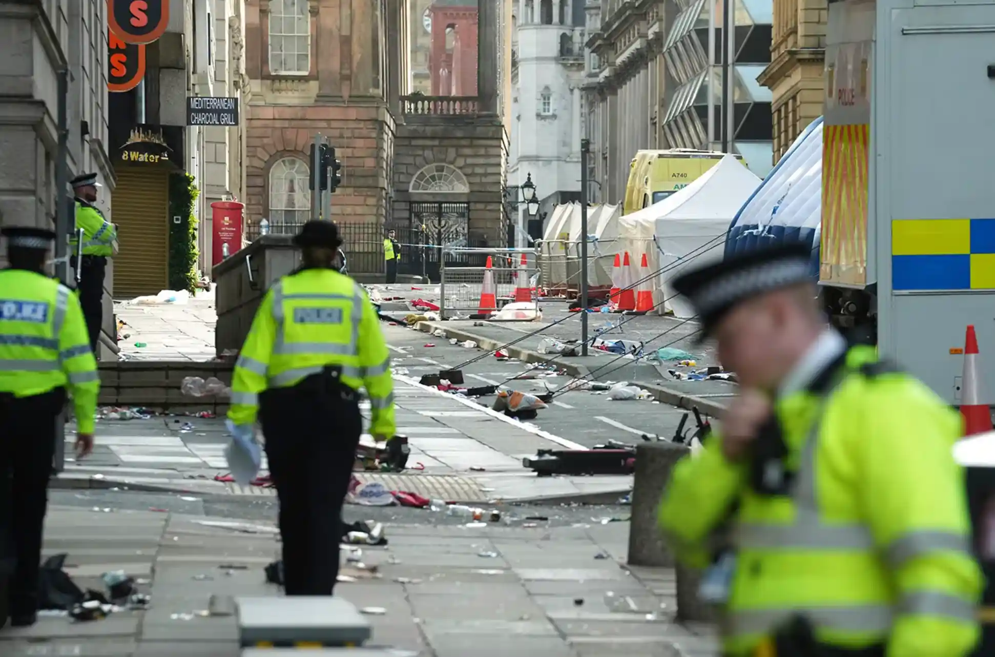 Police officers examine the road after a car collided with pedestrians during the Premier League winners parade in Liverpool, England.(AP Photo/Jon Super)