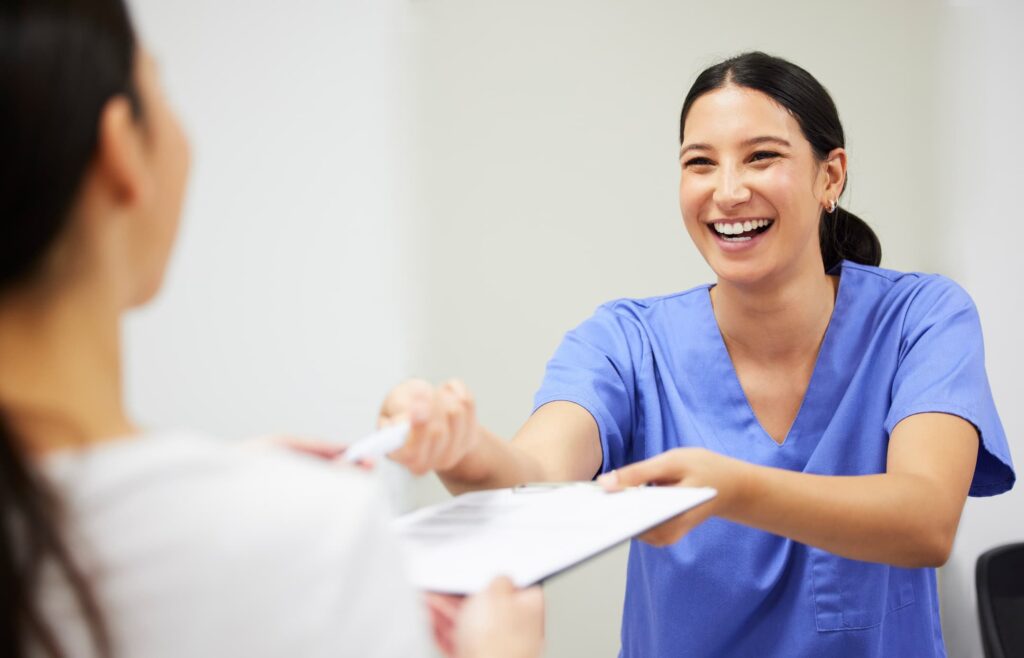 A physician assistant handing a clipboard over to a patient.