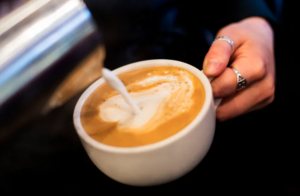 Photo of milk being poured into a coffee beverage.